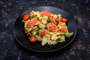 Marul, füme somon, kiraz domatesleri, salatalık ve susam tohumlu canlı bir salata renkli ve sağlıklı bir yemek sunar.