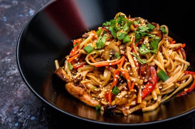 Lezzetli bir kase kızarmış erişte sebzelerle karıştırılmış susam tohumlarıyla süslenmiş lezzetli ve sağlıklı bir yemek için taze otlar.