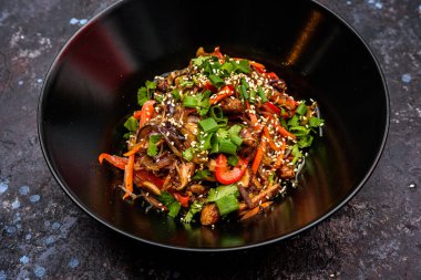 Karışık sebzeli, susam tohumlu ve taze otlu canlı bir tabak kızarmış cam şehriye sağlıklı ve lezzetli bir yemek oluşturur.