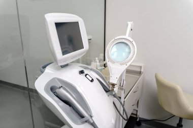 Profesyonel estetik kliniğinde ekran ve büyüteçle modern cilt bakım ekipmanlarına yakın çekim. Gelişmiş güzellik tedavilerine hazır.