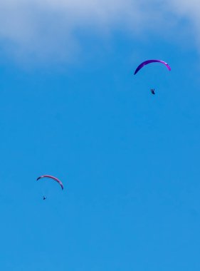 Mavi gökyüzündeki paraşütçüler.