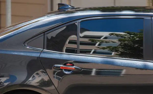 Şehirdeki modern bir araba yolcu penceresindeki bir binayı yansıtıyor.