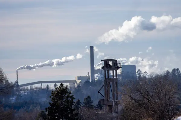 Mavi gökyüzüne karşı dumanı olan endüstriyel baca