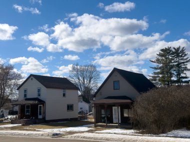 Karla kaplı ağaçlarla ve mavi gökyüzüyle banliyö evi