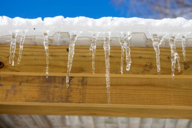 Çatıda buz saçakları ve mavi gökyüzü