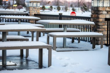Kar ve buzla kaplı bir restoranın dış masalarının kış manzarası.