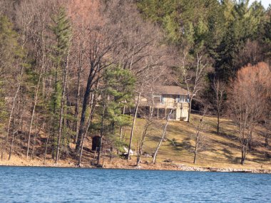 Ormanın ortasında, gölün kenarında bir ev.