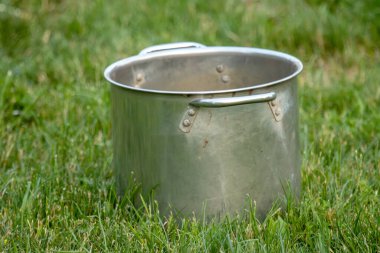 Bahçesinde yeşil çimen olan metal tencere, yakın plan.