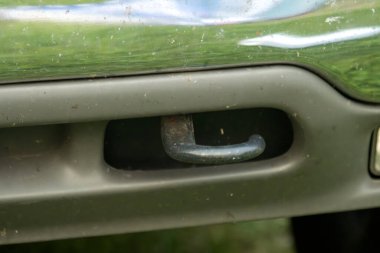 Krom tamponunda çimlerin ve gökyüzünün yansımaları olan bir arabanın yakın çekimi.