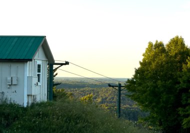 Mavi gökyüzünün altında yeşillikle çevrili ahşap bir çatının dikey görüntüsü.