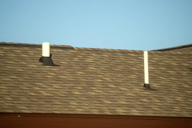 Mavi gökyüzü olan kiremitli bir çatıda alçak açılı havalandırma delikleri.