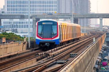 Gökyüzü treni tren istasyonuna varmak üzere. Demiryolu üzerindeki gökyüzü kasık treni istasyona varmak üzeredir. Arka plan ticaret binası ve şehir merkezidir.