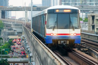 Gökyüzü treni tren istasyonuna varmak üzere. Demiryolu üzerindeki gökyüzü kasık treni istasyona varmak üzeredir. Arka plan ticaret binası ve şehir merkezidir.