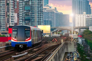 Gökyüzü treni gün batımında tren istasyonuna varacak. Demiryolu üzerindeki gökyüzü kasık treni istasyona varmak üzeredir. Arka plan ticaret binası ve şehir merkezidir.