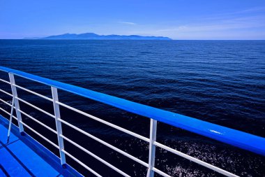 Detail of  railing of a boat with a deep blue water and sky in the backgroun