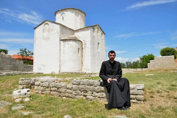 stock image Pastor upnik don Boo Bari in front of the Church of the Holy Cross, Crkva svetoga Kria, 9th century, the world's smallest cathedral, Nin, Zadar County, Dalmatia, Croatia, Europe