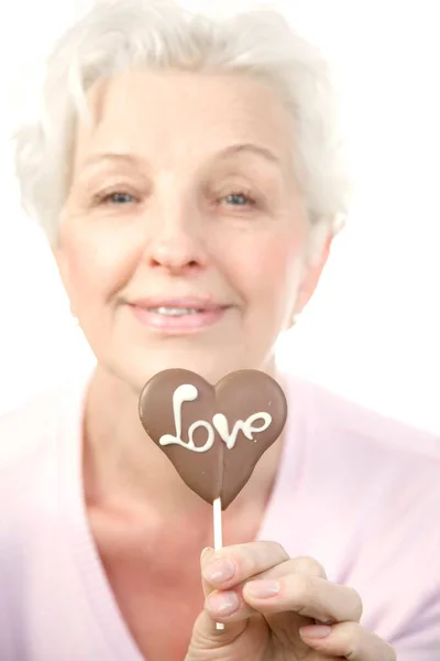 Μια Ώριμη Γυναίκα Που Κρατάει Μια Σοκολατένια Καρδιά Λέξη Αγάπη — Φωτογραφία Αρχείου