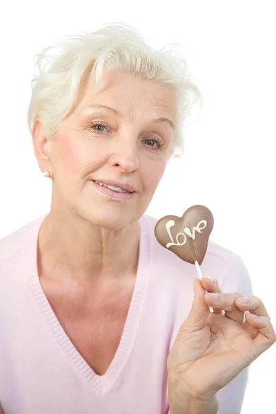 Uma Mulher Madura Segurando Coração Chocolate Com Palavra Amor Mão — Fotografia de Stock