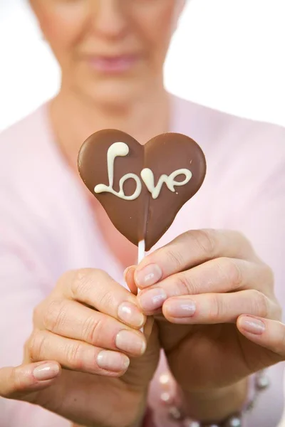 Uma Mulher Madura Segurando Coração Chocolate Com Palavra Amor Mão — Fotografia de Stock