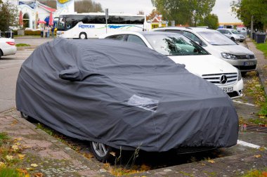 Mercedes, test vehicle covered with cover, parked at motorway service area clipart