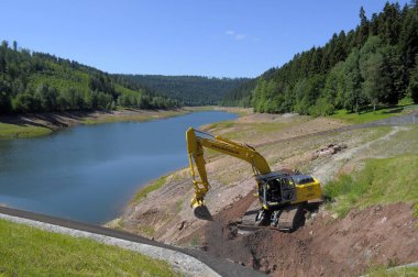 Northern Black Forest, Erzgrube reservoir, Nagoldtalsperre Erzgrube, summering, partially drained lake, dam wall, dredger at dam wall clipart