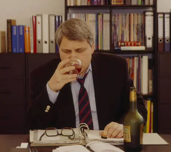 オフィスで酒を飲んでいる男 ストック写真