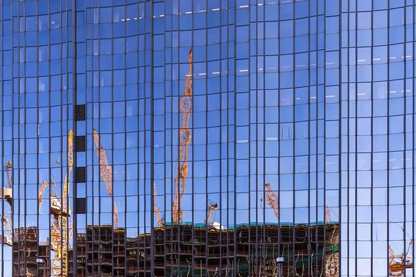 Building cranes and building site of the New Palace reflected in a glass facade of a high-rise building, Berlin, Germany, Europe