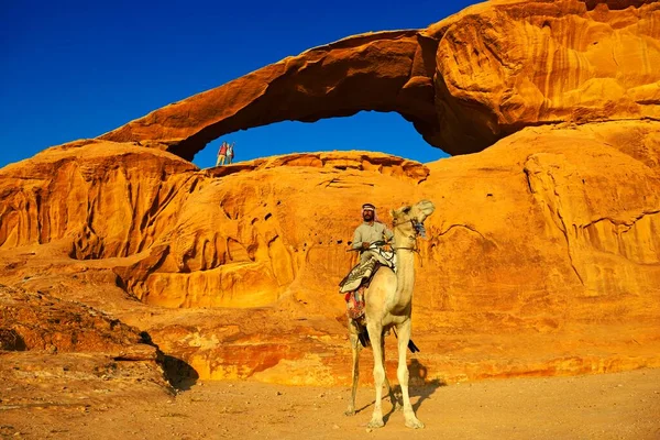 贝都因人骑着骆驼在约旦Wadi Rum的Rock Arch Kharza — 图库照片