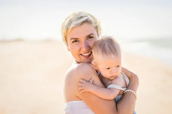 迷人的金发妈妈和4个月大的男婴在葡萄牙海滩玩耍 — 图库照片