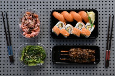 Sushi with UraMaki, Nigiri with salmon, Teriyaki skewers, Goma Wakame, algae salad, Chuka Ika Sansai, Octopus salad, Japanese chopsticks, in plastic packaging, Germany, Europe clipart