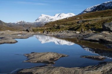 Okstindan mountain range, also Okstindene, with glacier Okstindbreen, water reflection in small mountain lake, Nordland, Norway, Europe clipart