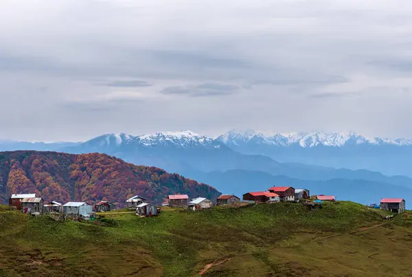 Sonbaharda Borcka Karagol çevresindeki ağaçlar ve ahşap evler. Sarı, turuncu, yeşil ve mavi karışımı. Doğa ve tatil eğitimi için uygun.