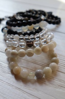 Beyaz ahşap arka planda bir sürü yarı değerli taş bileziği var..