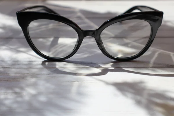 Γυαλιά Μαύρο Πλαίσιο Λευκό Ξύλινο Τραπέζι Στον Ήλιο — Φωτογραφία Αρχείου