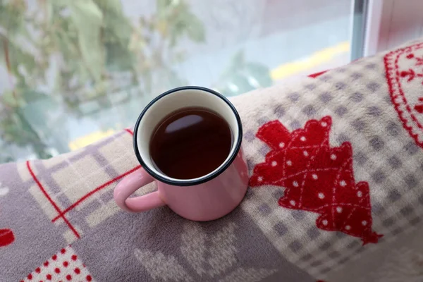 Cup of tea near window on a winter plaid.