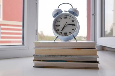 Pencerenin pervazında duran beyaz retro alarm saati. Okuma zamanı..