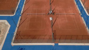 Güneşli bir günde boş kil tenis kortunun havadan görünüşü