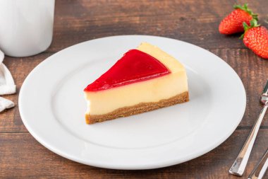 Lezzetli çilekli cheesecake, yanında kahve ve ahşap masa.