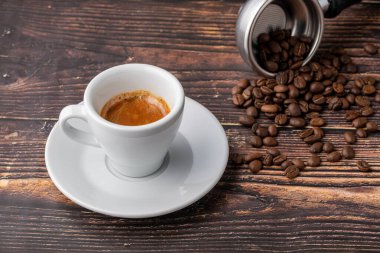 Taze espresso kahvesi, ahşap masada kahve çekirdekleri ile süslenmiş.