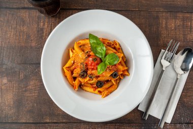 Domates soslu makarna, ahşap arka planda maydanozla süslenmiş domates.