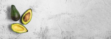 Beyaz taş masada hem kesiğin hem de olgun avokadonun üst görüntüsü