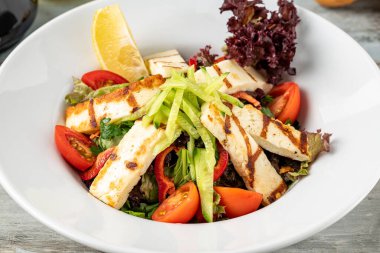 Domatesli salata ve ahşap masada halloumi peyniri.