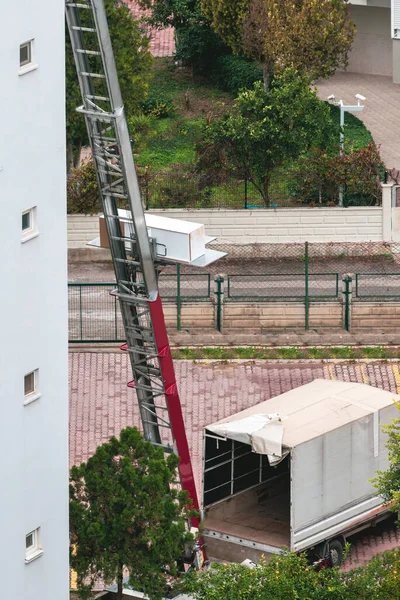 Home removal with hydraulic lift. Transporters carrying goods by elevator from the window of the building