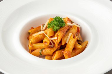 Domates soslu makarna, ahşap arka planda maydanozla süslenmiş domates.