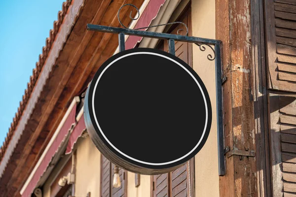 Blank signboard mockup hanging on the wall of the store in the street