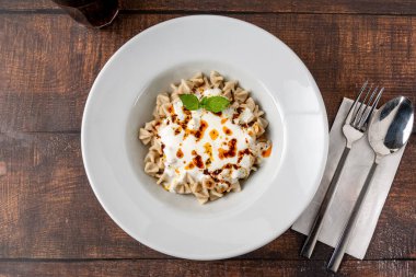 Tahta masadaki beyaz tabakta Kayseri ravioli veya Kayseri Mantisi.