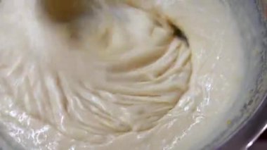 Woman beats milk, flour and eggs with mixer in a bowl to make cakes