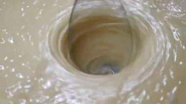 Woman beats milk, flour and eggs with mixer in a bowl to make cakes