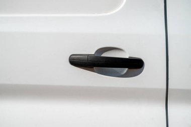 Black handle of sliding door of white colored van