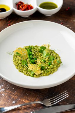 Güzel bir restoranda porselen tabakta bezelyeli risotto.